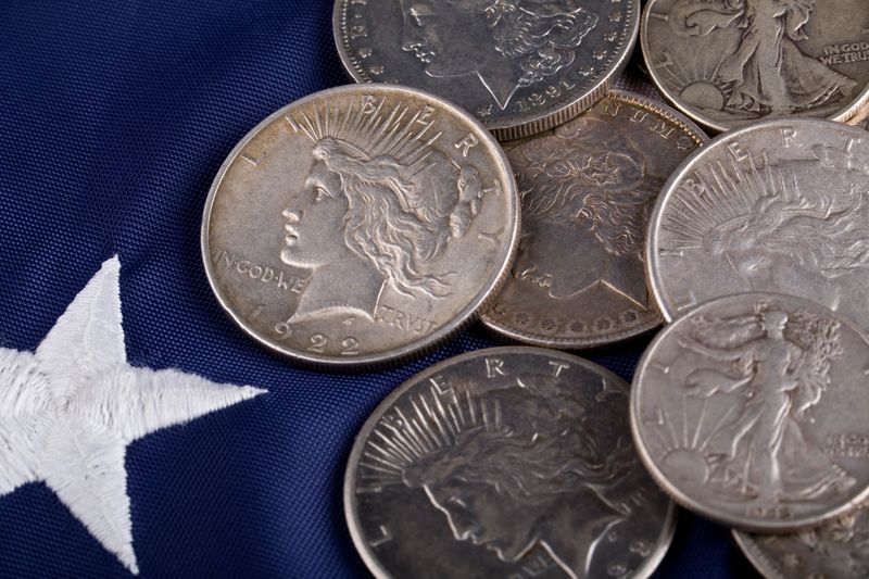 Morgan and Peace silver dollars on an American flag showing mint mark locations